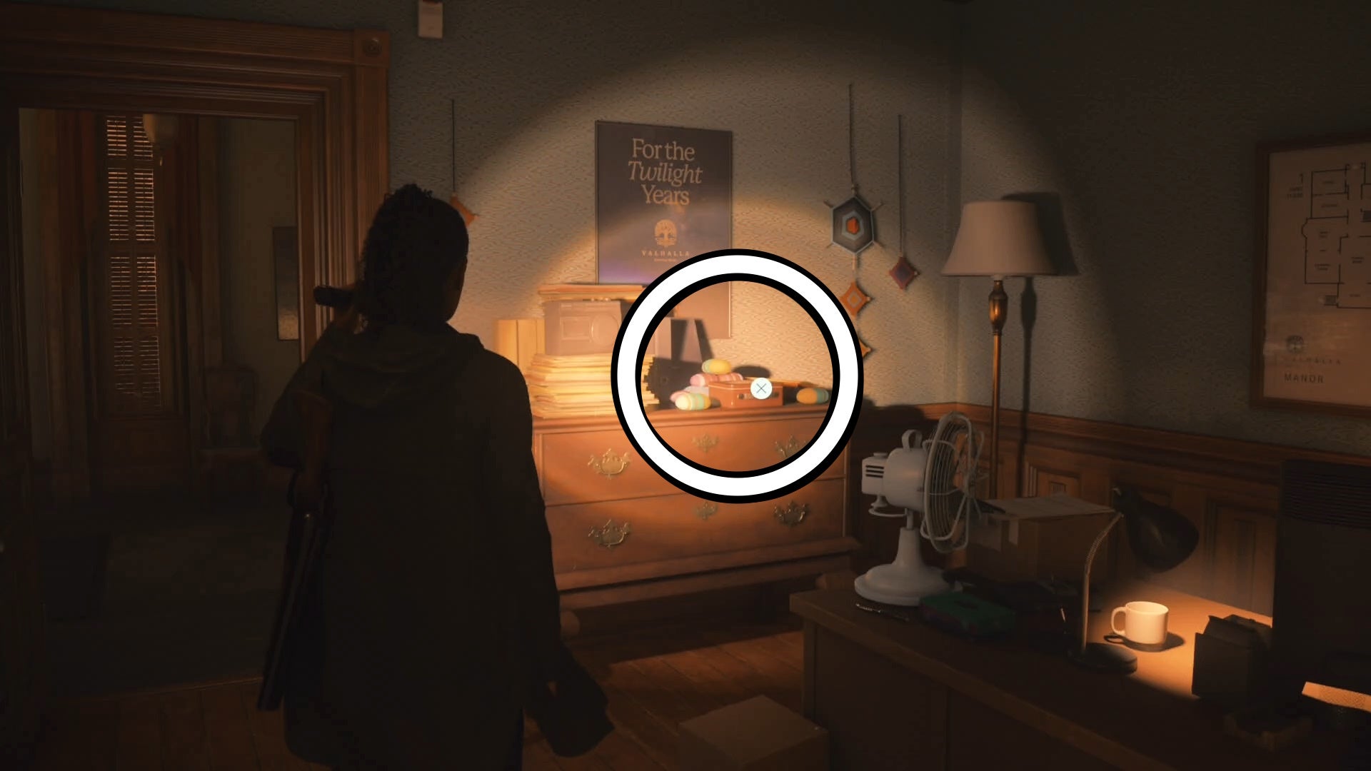 saga shining her flashlight on a lunch box on top of a messy drawer in an office