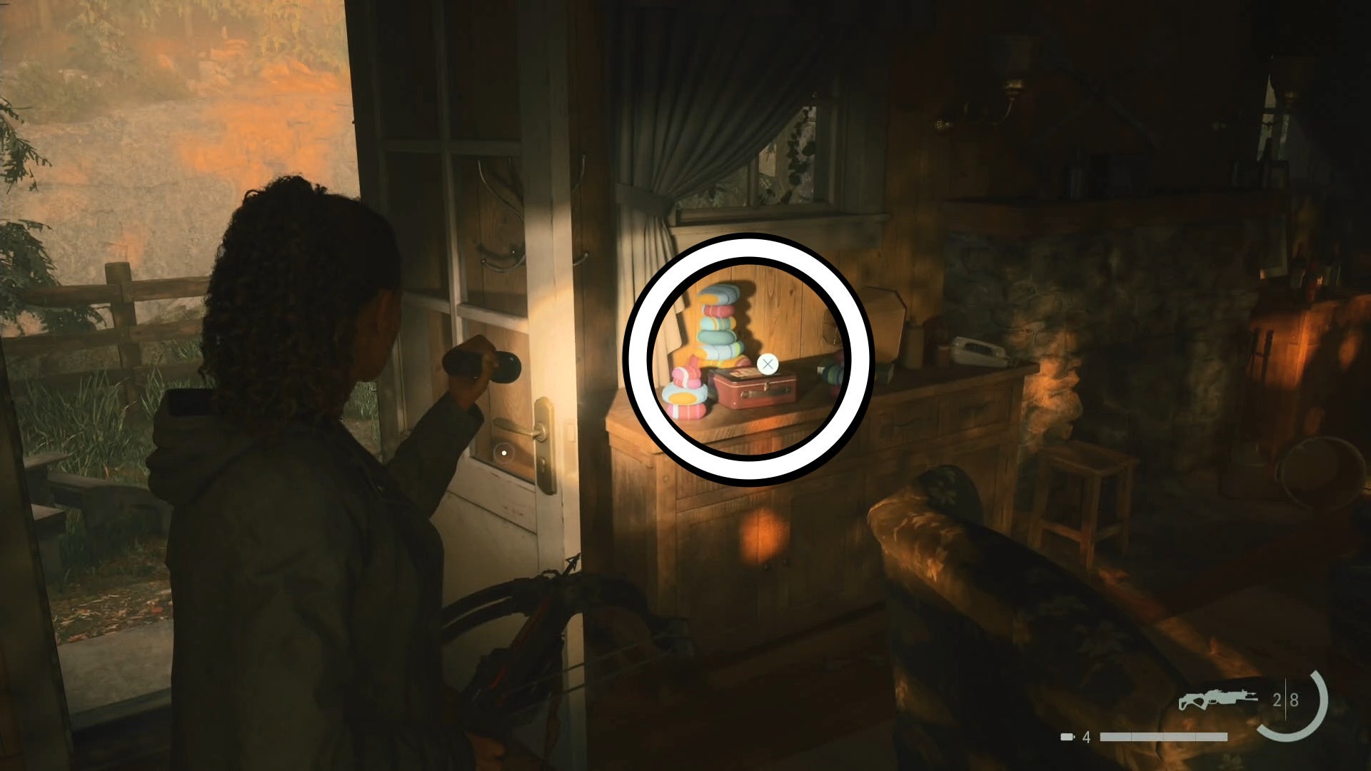 saga shining her flashlight on a lunch box on top of a drawer inside a wooden cabin, with the door open