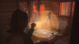 Saga shining her flashlight on a nursery rhyme setup in a cabin in the woods, which contains a standing camera and a note on the floor below the camera
