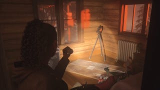 Saga shining her flashlight on a nursery rhyme setup in a cabin in the woods, which contains a standing camera and a note on the floor below the camera