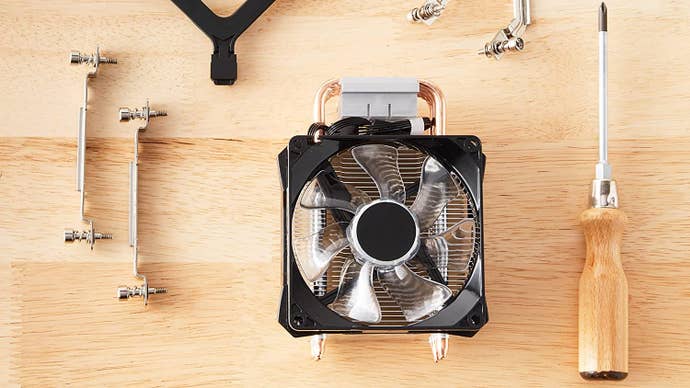 The Amazon Basics Computer Cooling Fan on a table, next to some of its mounting hardware and a screwdriver.