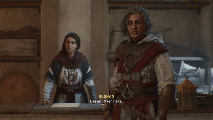 Roshan beckons Basim over to her and Rebekah in a Hidden Ones Bureau in Assassin’s Creed Mirage