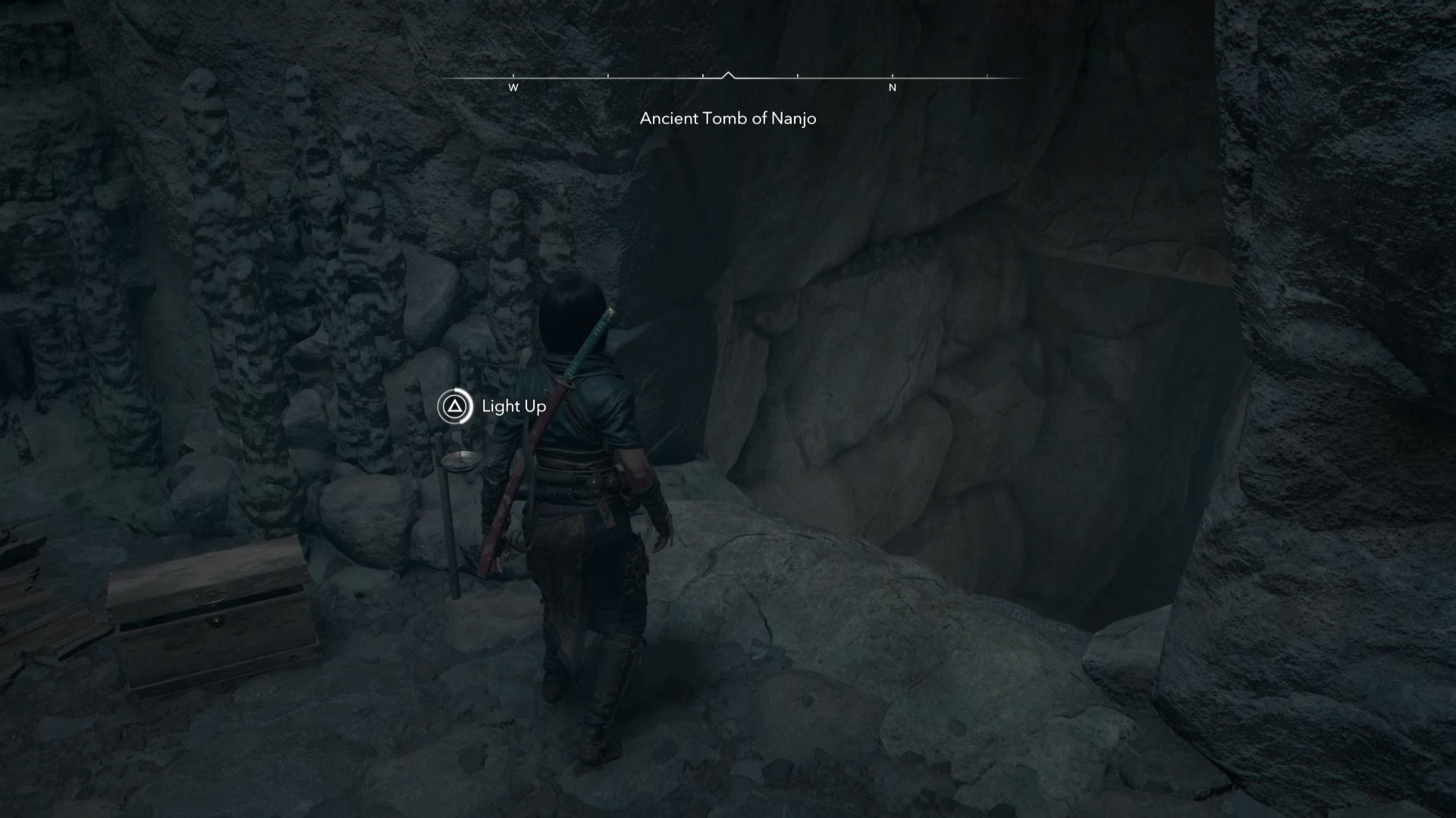 Naoe looking at a chest in a cave in Assassin&rsquo;s Creed Shadows.