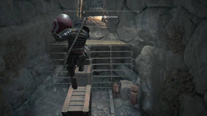 Yasuke holding a red jar and jumping across wooden blocks inside the Azuchi Kyotanyama Kofun in Assassin’s Creed Shadows.
