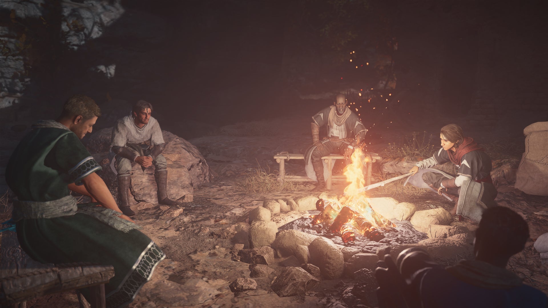 Basim and other Hidden Ones are gathered around a campfire in Assassin's Creed: Mirage - 1