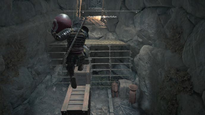 Yasuke holding a red pot and jumping through wooden blocks inside the Azuchi Kyotanyama Kofun in the Shadows of Creed of Assassin.