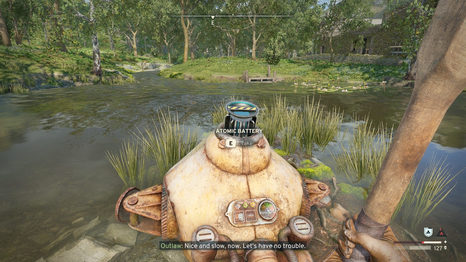 The player faces a dead robot in a river who has an Atomic Battery sticking out of them in Atomfall - 9