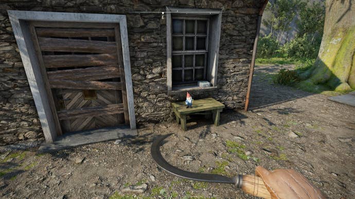 The player looks at a gnome sat on a small table in front of an abandoned outhouse in Wyndham Village in Atomfall