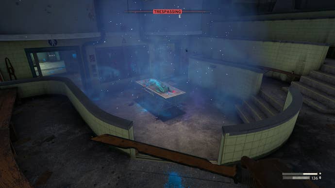 The player, inside of the auditorium on the lower level of medical, looks at a medical table where Sample One can be found in Atomfall