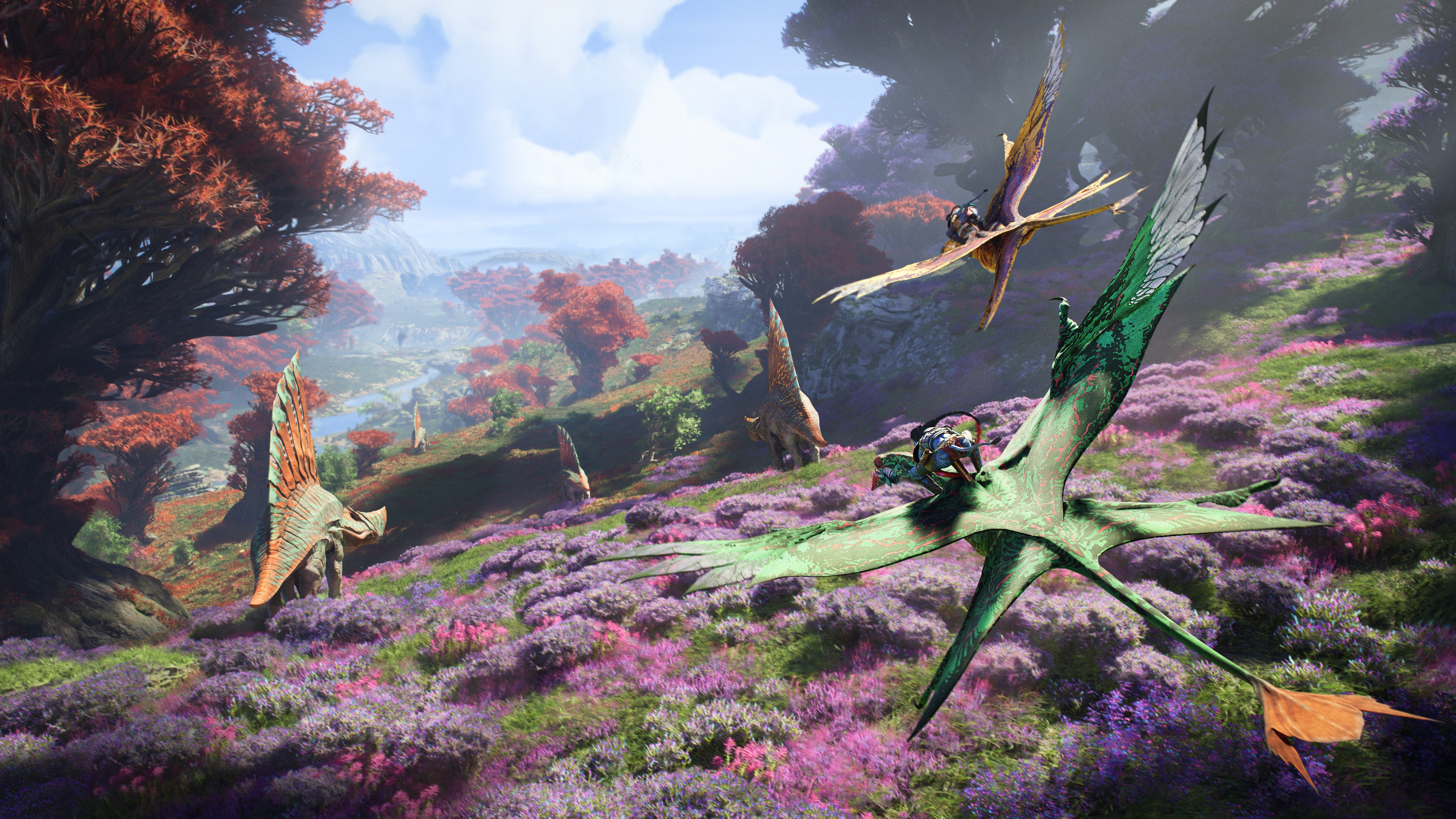 Two Na&rsquo;vi characters flying on large lizard birds through the world of Pandora, which is lush and green with purple and red foliage, and dinosaur-like creatures ambling around.