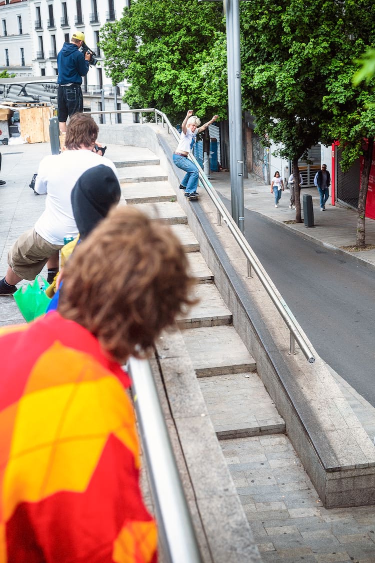 Breana Geering skateboarding down the ramp alongside a stairwell in a city with people watching. - 9