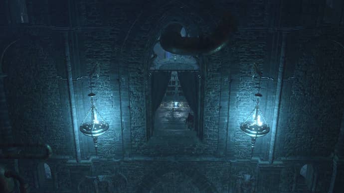A dark tower wall lit up by two braziers containing blue flames.