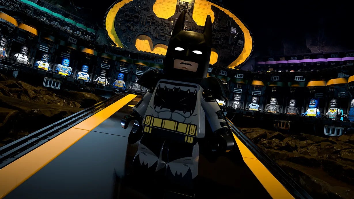 Batman stands in front of his many different Batsuits within the Batcave in Lego Batman Legacy of the Dark Knight