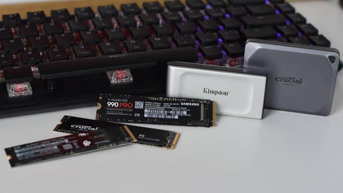 Several SSDs laid out in front of a gaming keyboard.