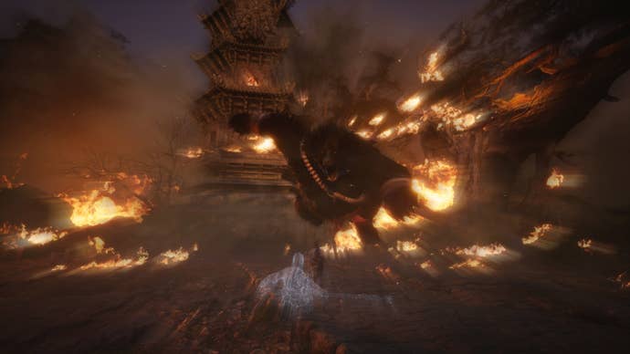 Wukong fights a massive bear in an arena besieged by fire in Black Myth Wukong.