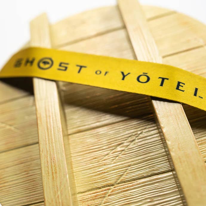 Close up of the Ghost of Yotei popcorn bucket showing a yellow strap with the game name written on it