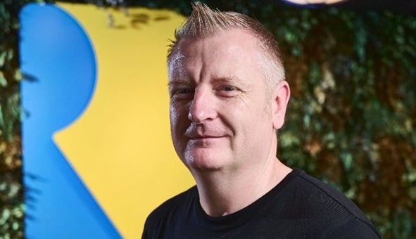 Craig Duncan stands in front of Rare's logo