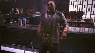 solomon reed in a sparkling suit and sunglasses leaning against a bar