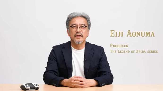 Eiji Aonuma wearing a white top and black jacket sits in front of a Nintendo Switch controller as he introduces an update on Zelda: Tears of the Kingdom