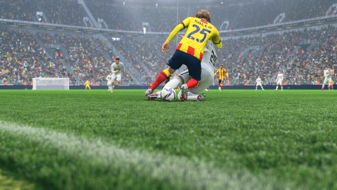 Ein Spieler führt in der Nähe des Spielfeldrandes eine Grätsche gegen einen Gegner durch.
