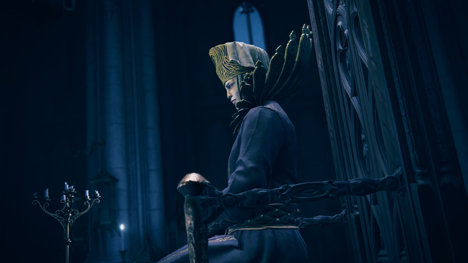 Grand looking figure with huge collar and headdress sits atop a throne in moonlight