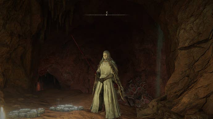 The player stands outside of the entrance to Caelid’s Abandoned Cave in Elden Ring