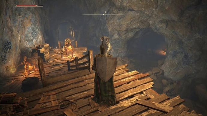 Armored figure watching the miners working in the veins of the Limgrave Tunnels in Elden Ring.