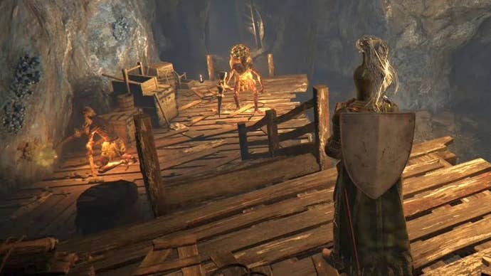 Armoured character looking at miners working veins in the Limgrave Tunnels in Elden Ring.