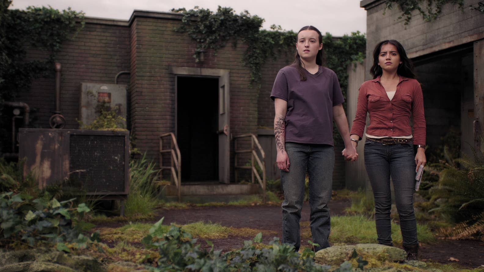 Ellie and Dina hold hands as they look out over Seattle in The Last of Us season two