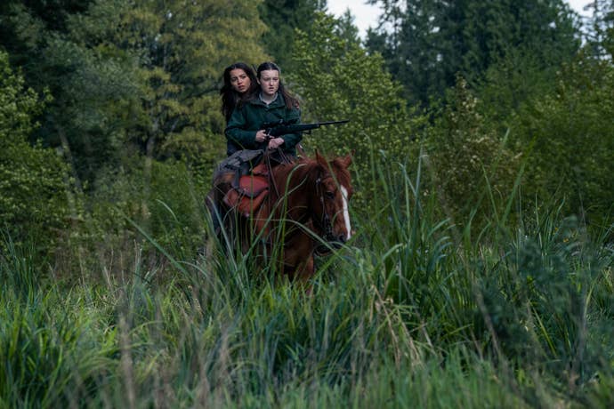 Ellie and Dina riding a horse through a lush landscape in TLOU season two