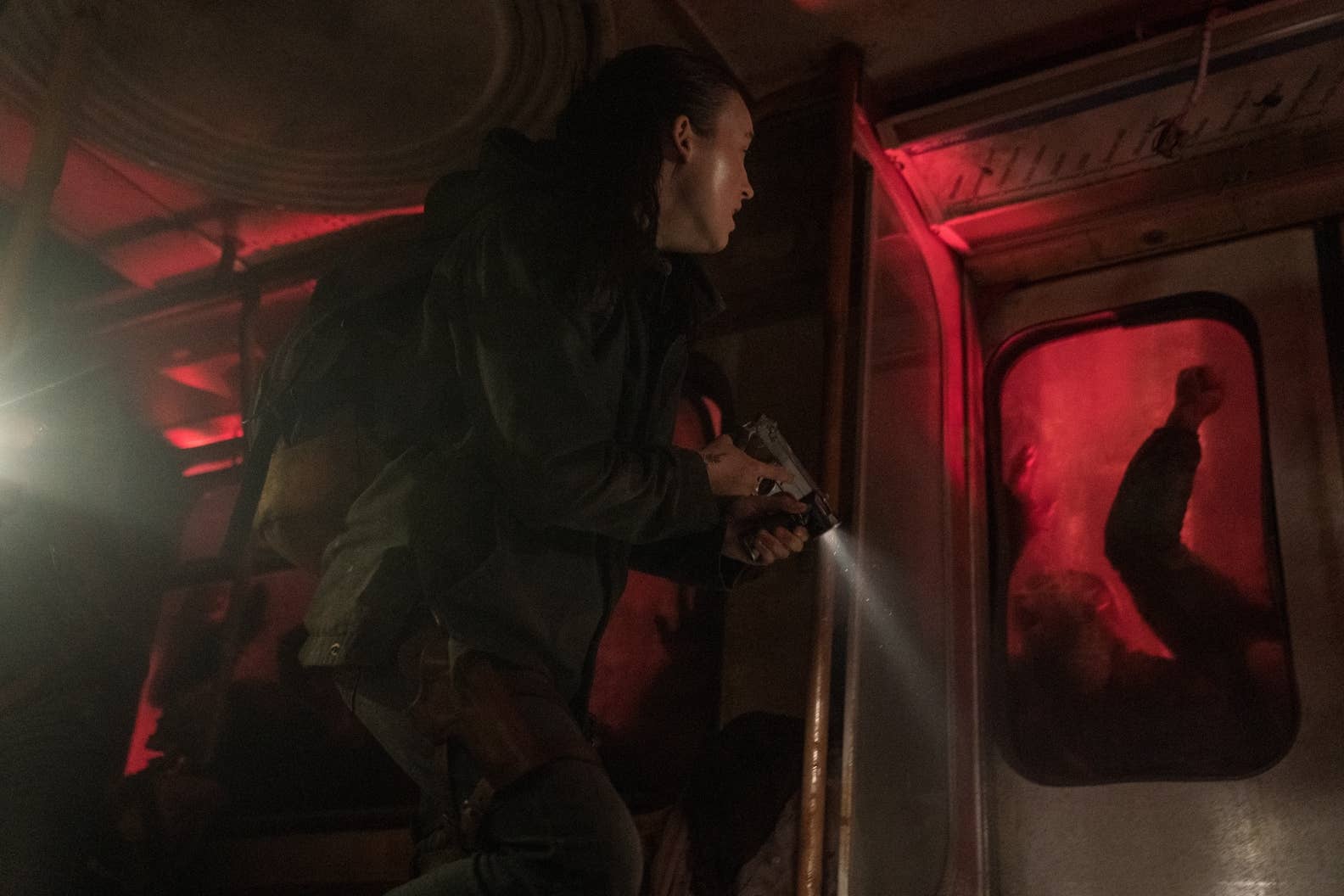 Ellie in a train which is being attacked by infected in The Last of Us season two