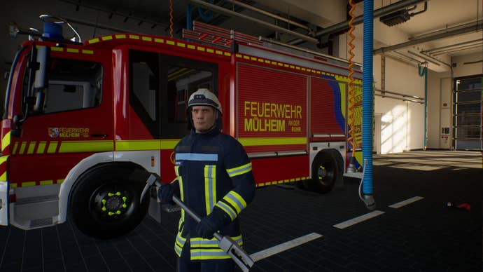 A firefighter is stood in uniform in front of a fire engine.