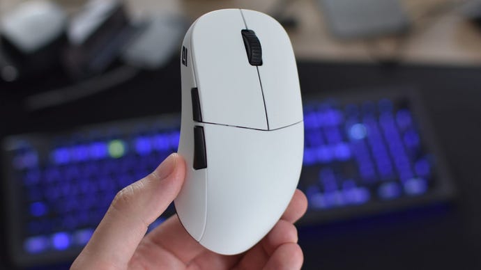 The Endgame Gear XM2WE gaming mouse being held up in front of a keyboard.