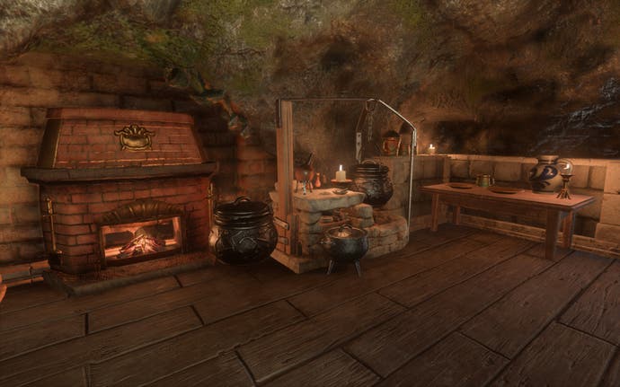 A kitchen inside a cosy hobbit hole, complete with kettles, pots and pans, candles and a roaring brick fireplace.