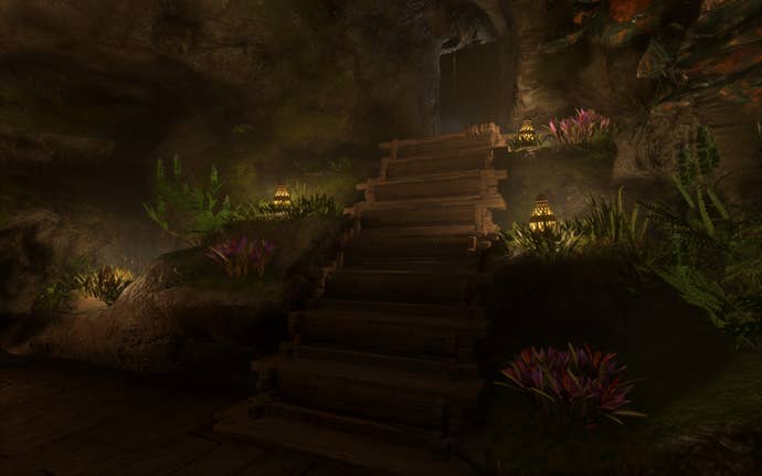 A wooden staircase leads down into an underground room. At the side of the staircase are tufts of grass and flowers, with firefly lamps placed on the floor to create a magical fairy theme.