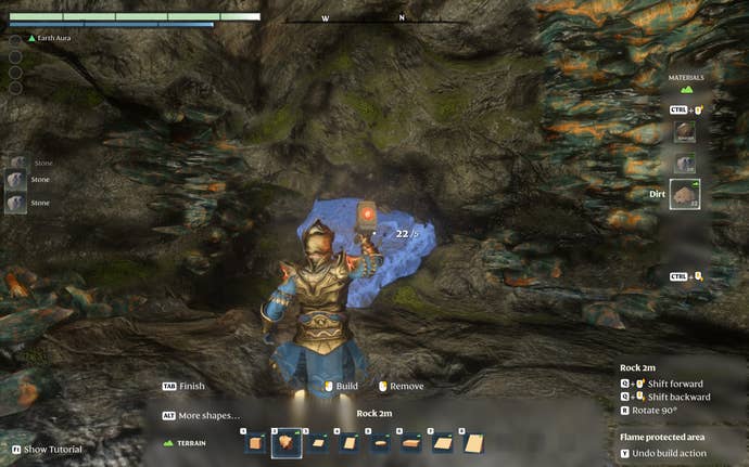 The player-character, using Enshrouded’s building system, deletes terrain in the shape of a lumpy block. The building system shows a preview of this as a glowing outline.