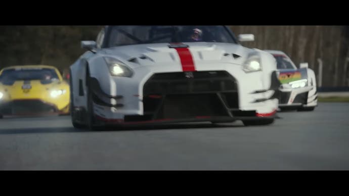 Gran Turismo movie trailer screenshot showing Jann's white car in front of two others on the track, facing towards the cars from low down as they drive towards the camera