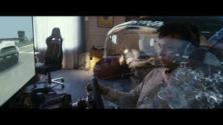 Gran Turismo movie trailer screenshot showing Jann gaming in his home racing setup, virtual car forming around him