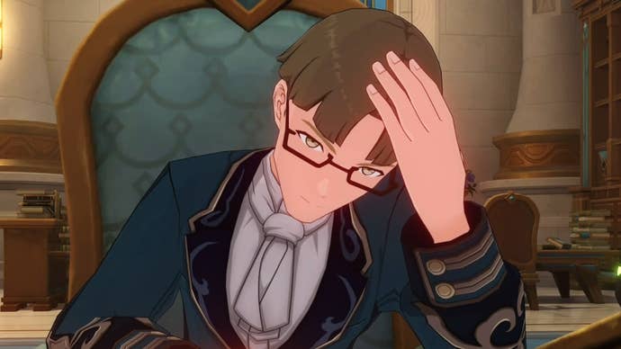 Ianune sitting on a blue chair with his hand on his head.