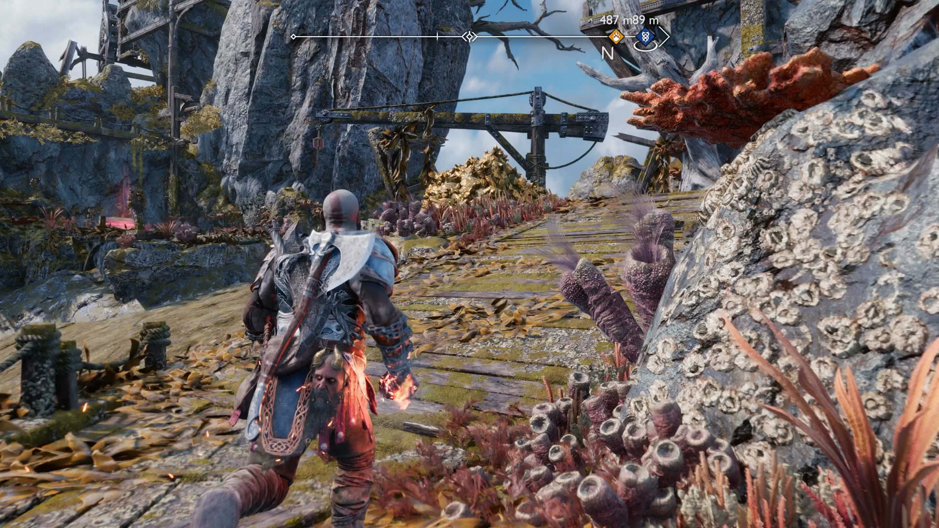Kratos uncovering a secret path using a firebomb to destroy a deposit of golden rocks in God of War Ragnarok