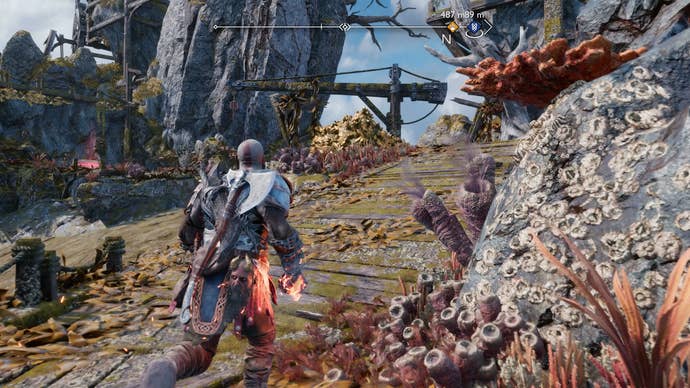 Kratos uncovering a secret path using a firebomb to destroy a deposit of golden rocks in God of War Ragnarok