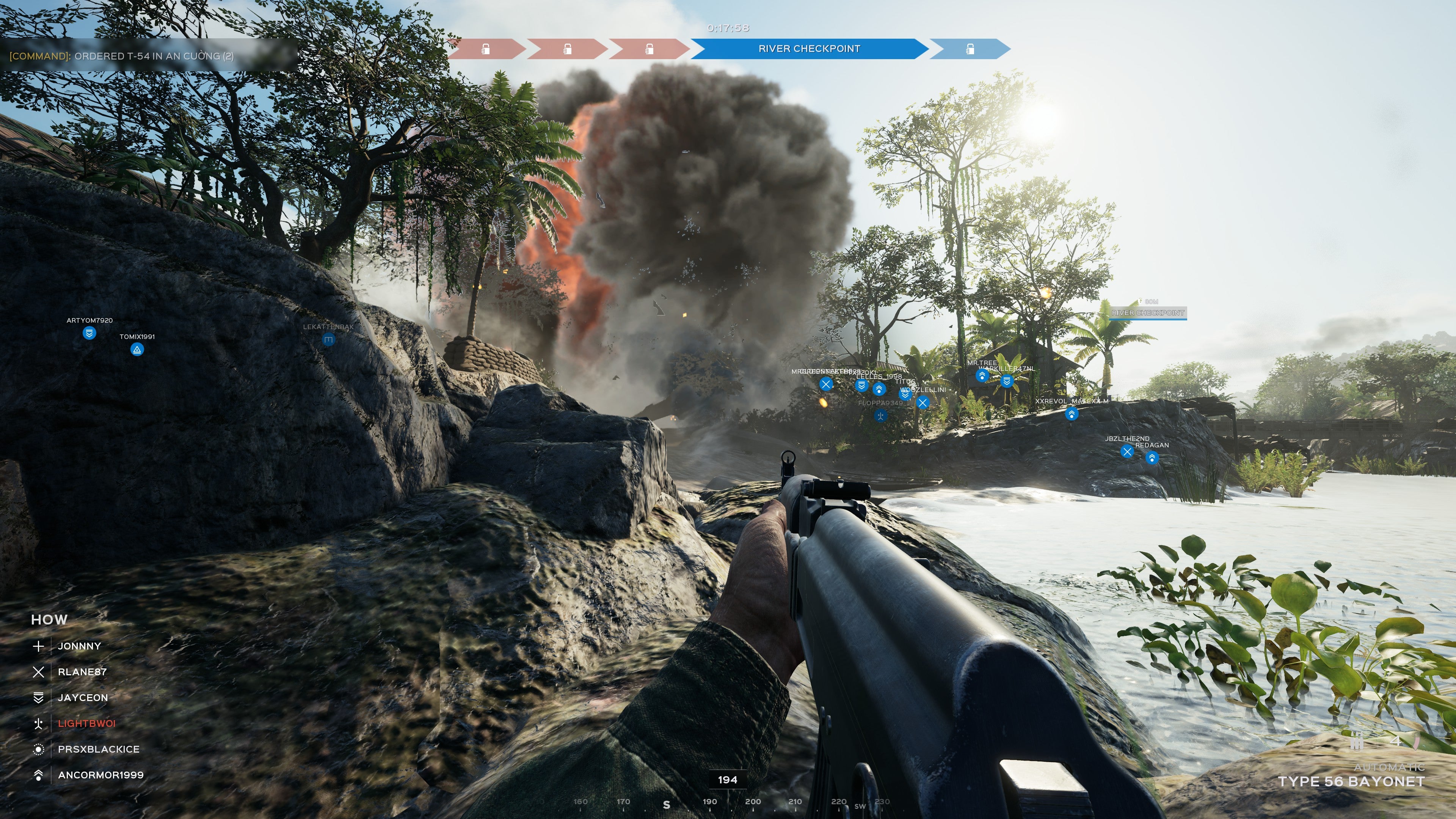 A Screenshot of Hell Let Loose: Vietnam, showing the player lying on some rocks beside a river, as a bomb detonates a few yards in front of him.
