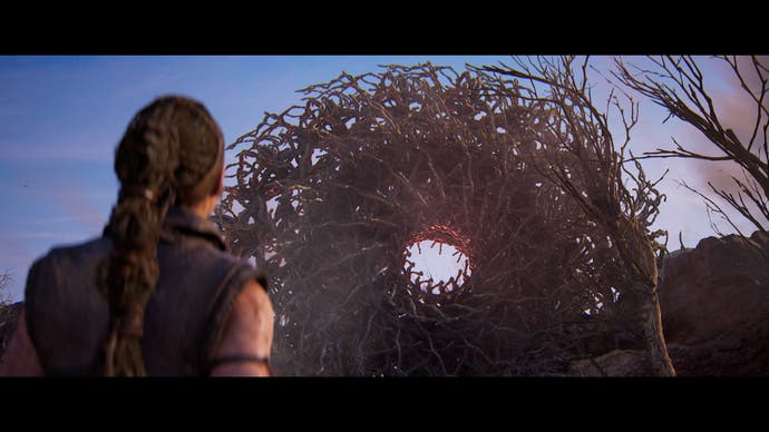 Hellblade 2 screenshot showing Senua standing in front of a large, circular barrier made of interlocking sticks