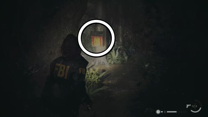 saga looking at a red supply box on a tree in dark woods with a white circle around the box