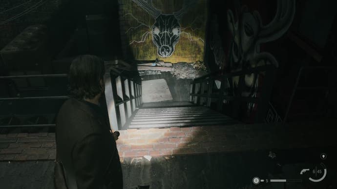 alan shining his flashlight down a staircase on a rooftop, with yellow and black graffiti on a wall at the bottom of the stairs depicting a deer