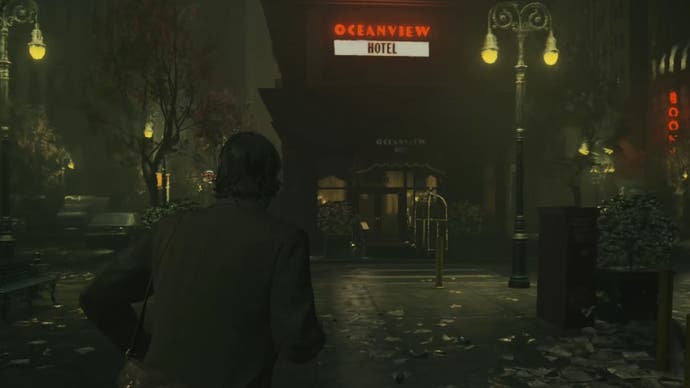 cropped image of alan looking up at the oceanview hotel on a dark street, with dull streetlamps on either side and the hotel sign flashing red and white