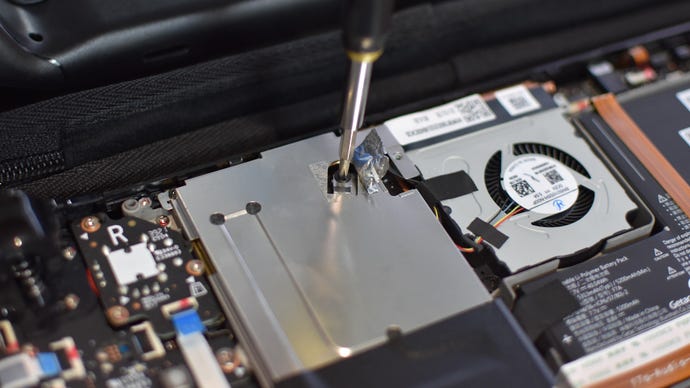 Step 4 of how to install an SSD in a Steam Deck: On LCD models, remove all screws holding the large metal cover in place and remove it. On older models, peel back the small piece of foil to reveal a third screw.