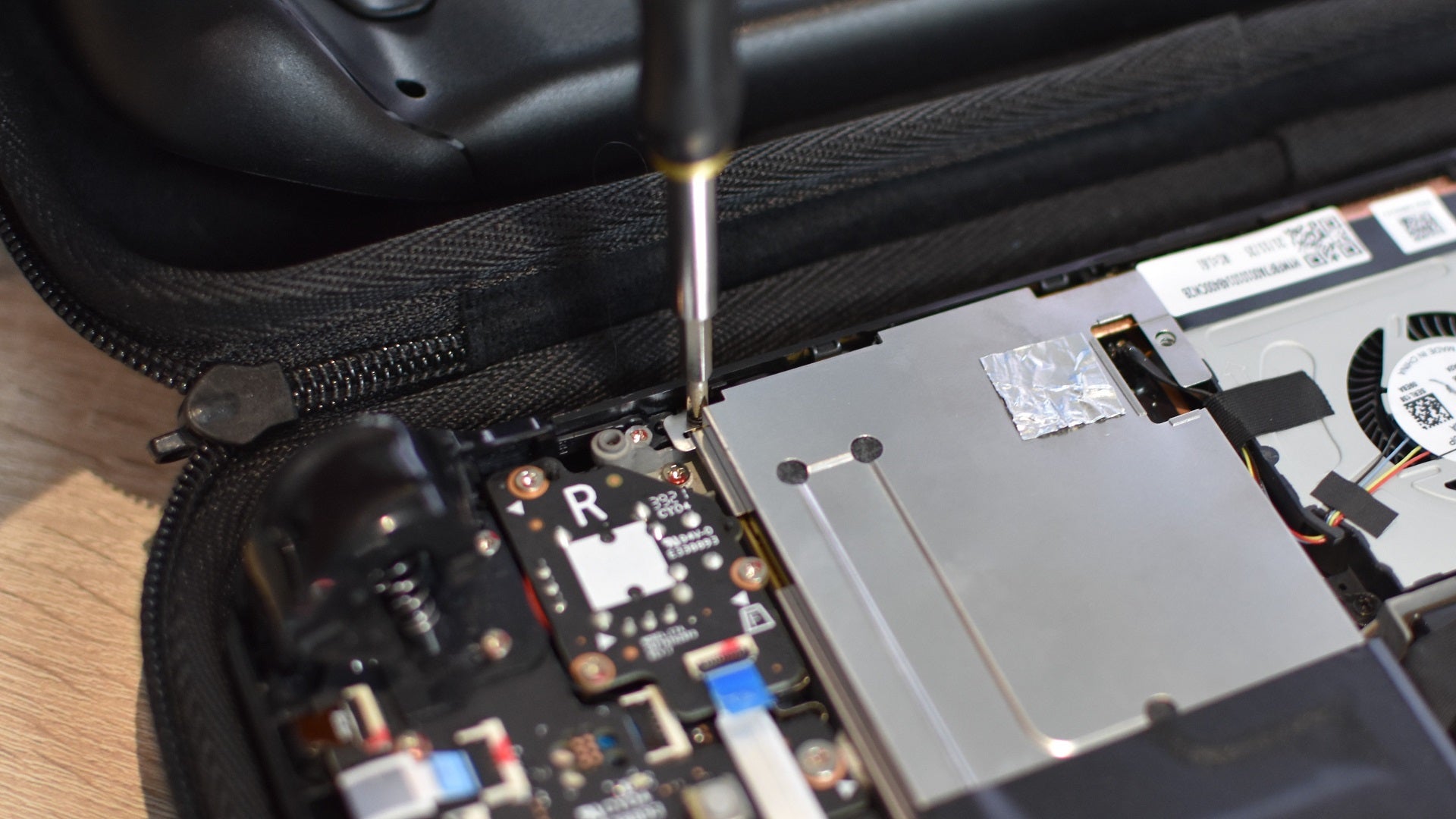 Step of how to install an SSD in a Steam Deck: On LCD models, reconnect the battery cable and replace the metal cover. On older models, flatten the foil section back down. - 15