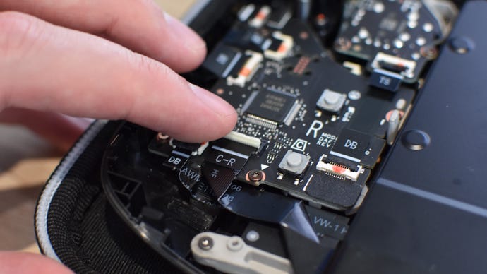 Step 9 of how to install an SSD in a Steam Deck: On a Steam Deck OLED, reconnect the battery connectot, then reattach the ribbon cable. Then, screw the metal plate back into place.
