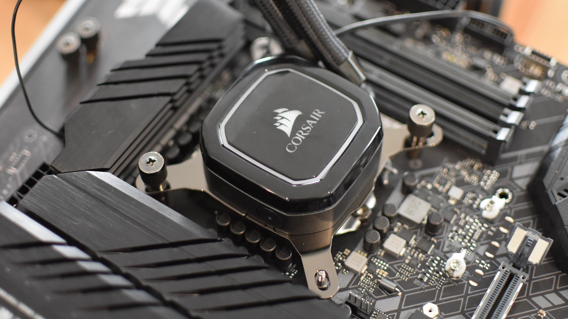 Step 4 of how to install a CPU liquid cooler: press the pump down on the CPU and attach it to the backplate.